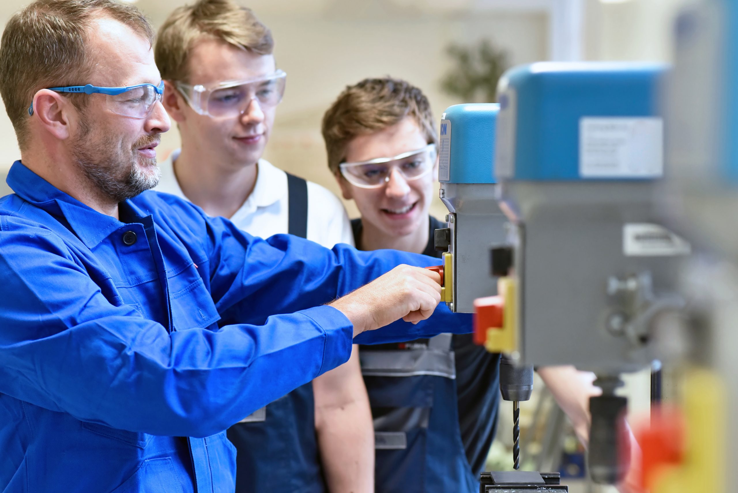 Group of young people in mechanical vocational training with teacher at drilling machine // Berufsausbildung – Jugendliche und Lehrer in der Berufsschule