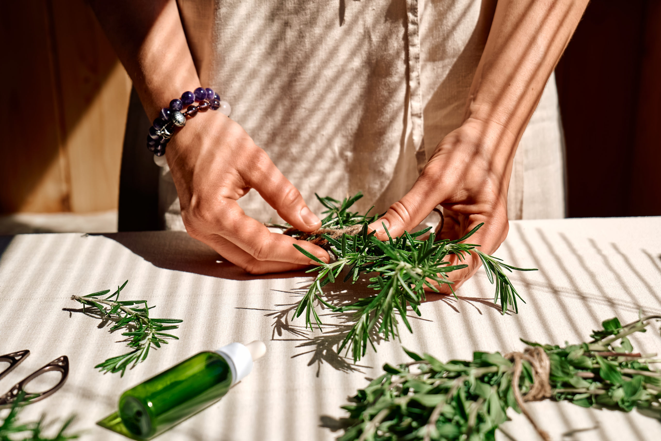 alternative medicine. women's hands tie a bunch of rosemary. woman herbalist preparing fresh fragrant organic herbs for natural herbal treatments.